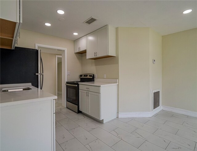 kitchen with fridge, stainless steel range with electric cooktop, and white cabinetry