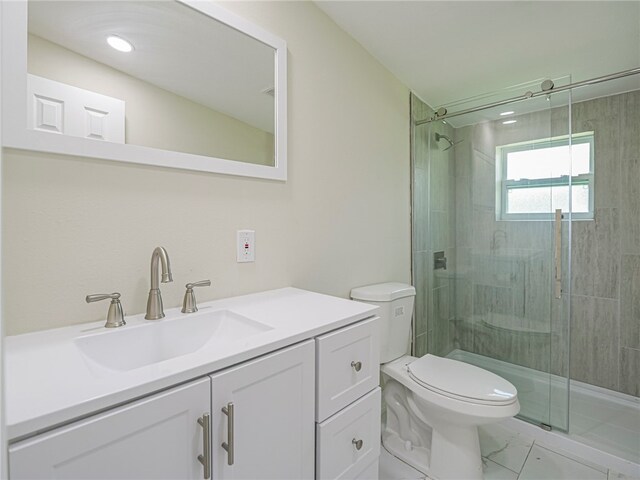 bathroom with vanity, toilet, and a shower with door