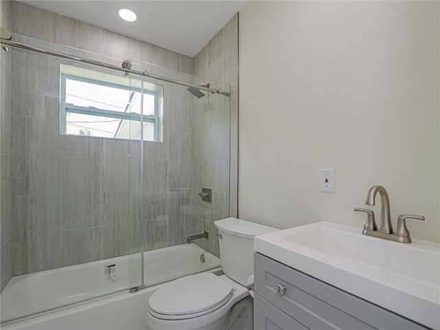 full bathroom with vanity, combined bath / shower with glass door, and toilet