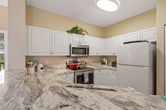 kitchen featuring light stone countertops, stainless steel appliances, and white cabinetry