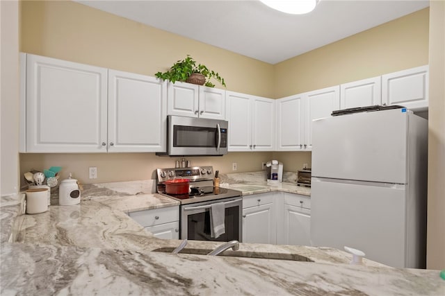 kitchen featuring white cabinets, stainless steel appliances, and light stone countertops