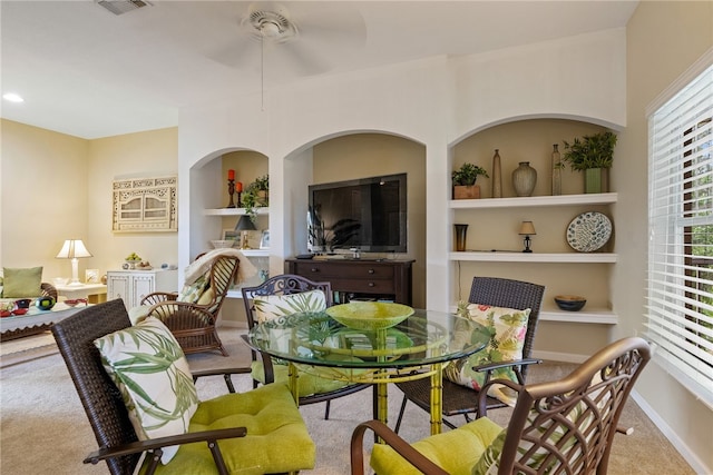 carpeted dining room with ceiling fan and built in features