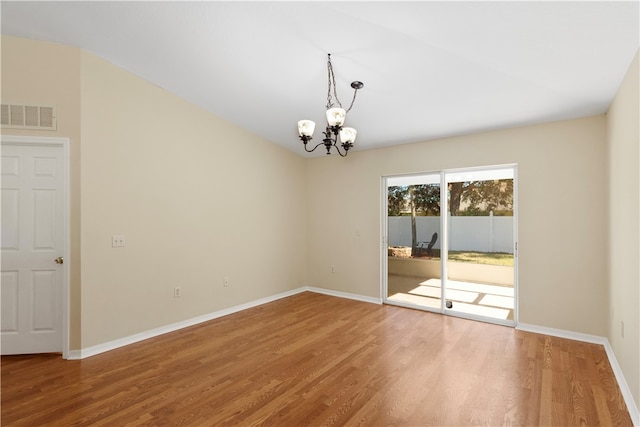 unfurnished room featuring hardwood / wood-style floors and an inviting chandelier