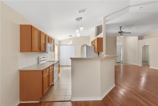 kitchen featuring light wood-type flooring, white appliances, vaulted ceiling, ceiling fan, and pendant lighting