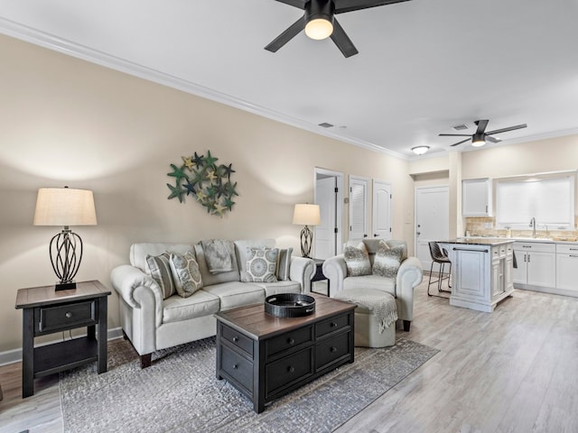 living room featuring light hardwood / wood-style flooring, ceiling fan, and crown molding