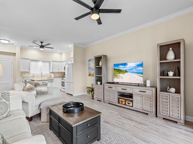 living room with light hardwood / wood-style floors, ceiling fan, sink, and crown molding