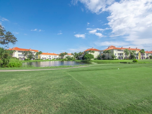 view of home's community with a water view and a lawn