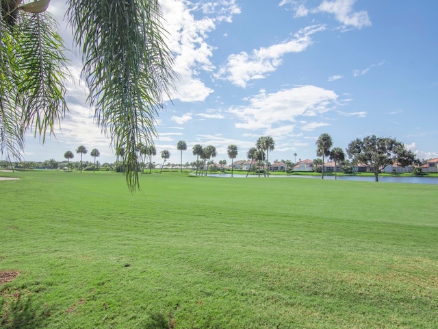 surrounding community with a water view and a lawn