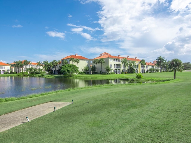 view of property's community with a water view and a lawn