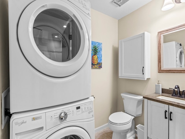 bathroom featuring stacked washing maching and dryer, tile patterned flooring, vanity, and toilet