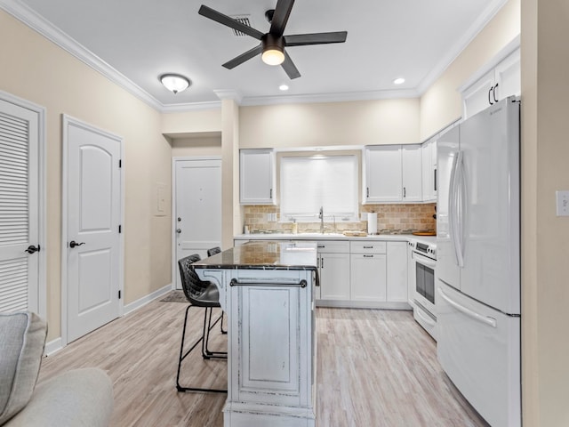 kitchen featuring light hardwood / wood-style floors, white cabinets, a breakfast bar area, a kitchen island, and white appliances