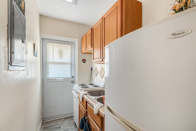 kitchen with white appliances, a textured ceiling, and light hardwood / wood-style floors