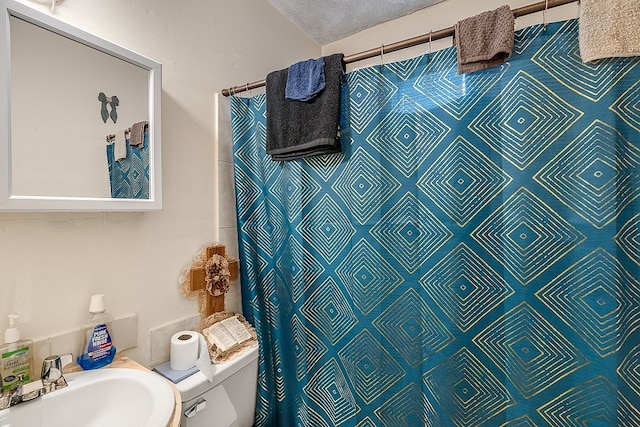 bathroom featuring a shower with shower curtain, a textured ceiling, toilet, and sink