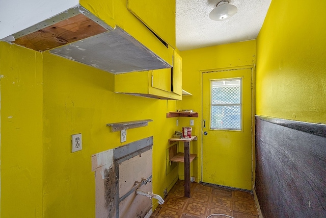 clothes washing area with a textured ceiling