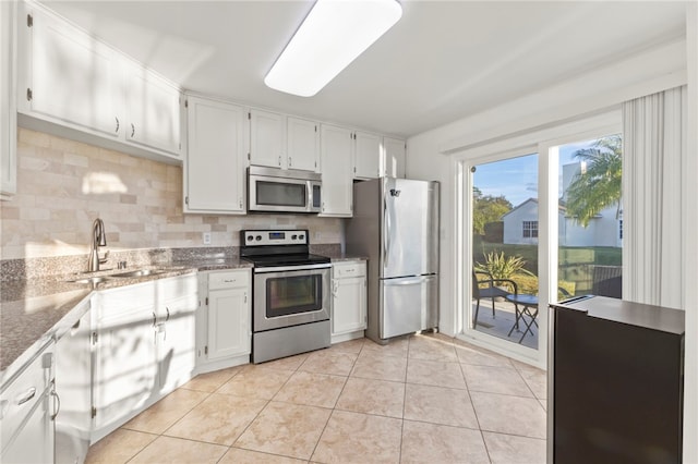 kitchen featuring tasteful backsplash, white cabinetry, sink, light tile patterned floors, and stainless steel appliances