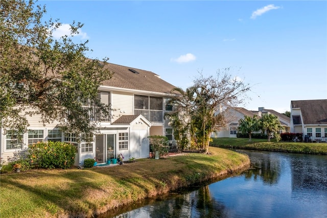 rear view of house featuring a lawn, a sunroom, and a water view