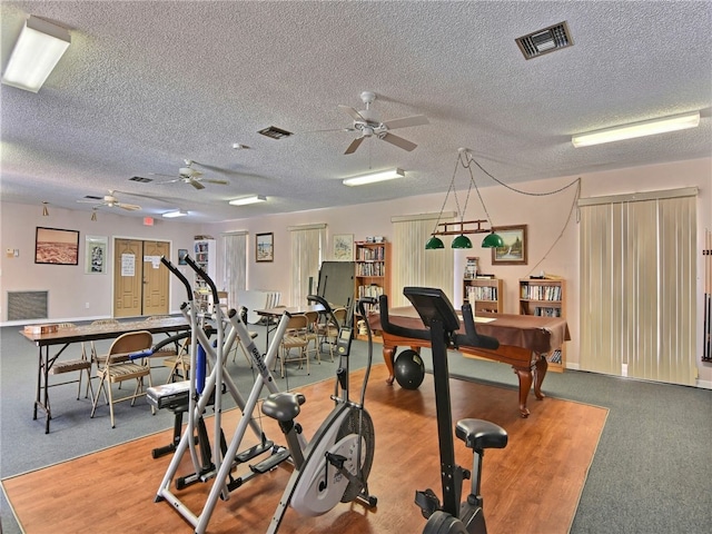 gym with pool table, a textured ceiling, ceiling fan, and wood-type flooring