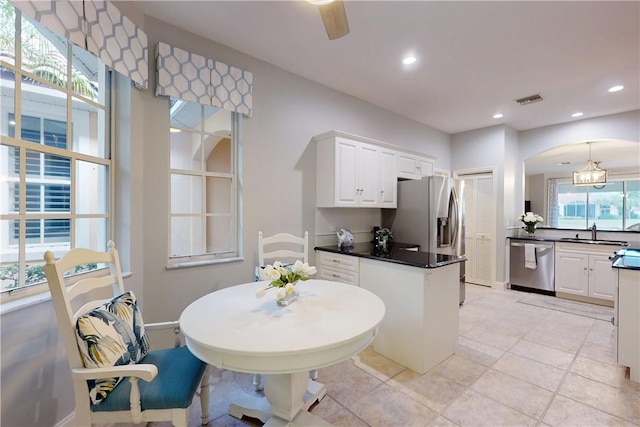 kitchen with appliances with stainless steel finishes, pendant lighting, sink, white cabinets, and ceiling fan