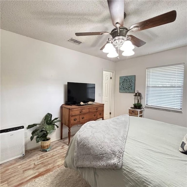 bedroom featuring ceiling fan, hardwood / wood-style floors, and a textured ceiling