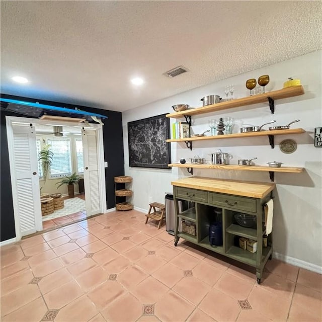 bar with wood counters, light tile patterned floors, a textured ceiling, and green cabinets