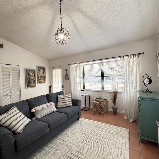 living room featuring vaulted ceiling, a textured ceiling, and light tile patterned floors