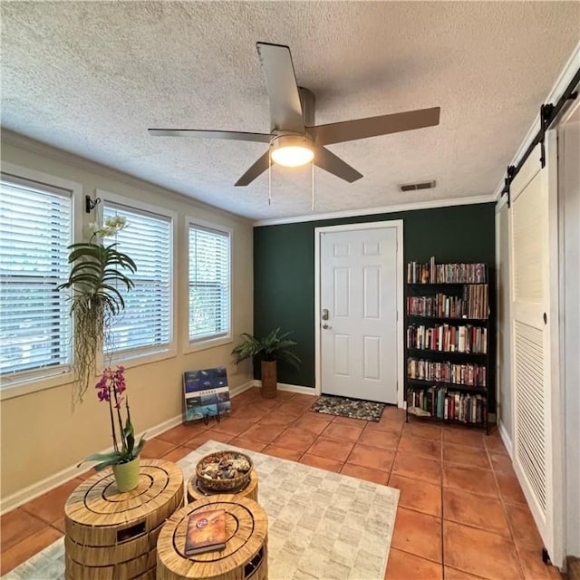 sitting room with tile patterned flooring, plenty of natural light, a barn door, and ceiling fan