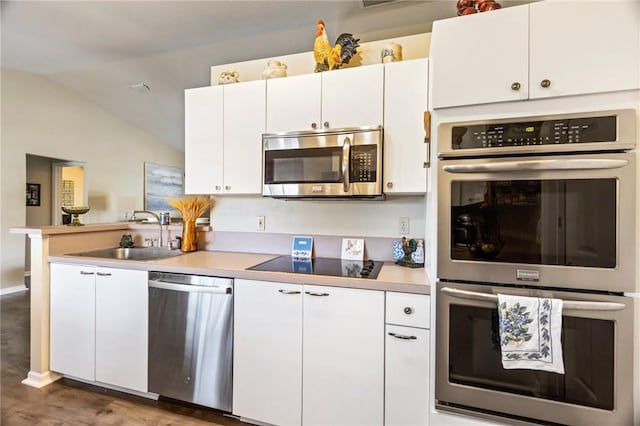 kitchen featuring stainless steel appliances, vaulted ceiling, white cabinets, and a sink