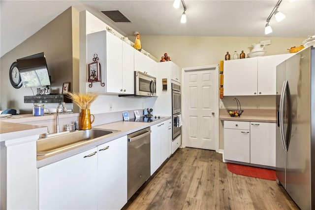 kitchen featuring vaulted ceiling, visible vents, stainless steel appliances, and wood finished floors