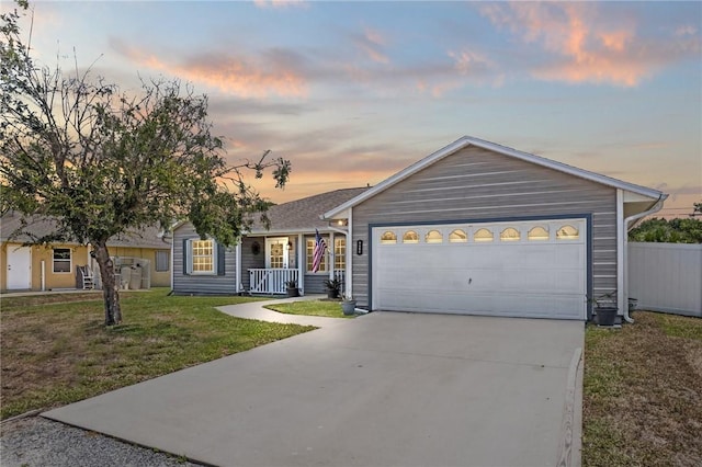 ranch-style house featuring covered porch, concrete driveway, a front lawn, and an attached garage