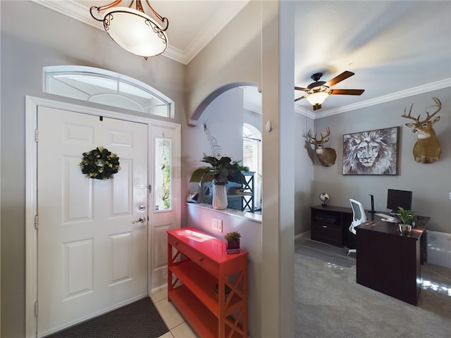 carpeted entryway with crown molding and ceiling fan