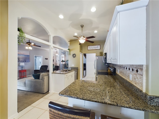 kitchen featuring appliances with stainless steel finishes, white cabinetry, sink, a breakfast bar area, and kitchen peninsula