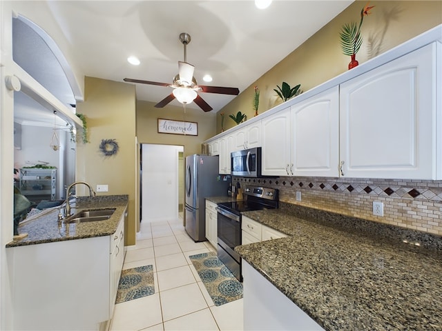 kitchen with appliances with stainless steel finishes, sink, white cabinets, decorative backsplash, and dark stone counters