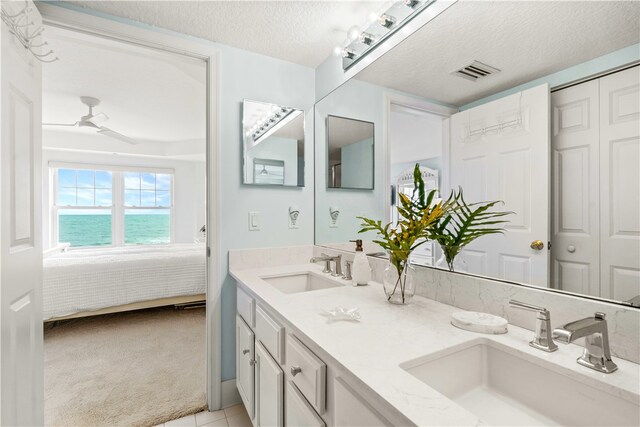 bathroom with vanity, tile patterned floors, a water view, ceiling fan, and a textured ceiling