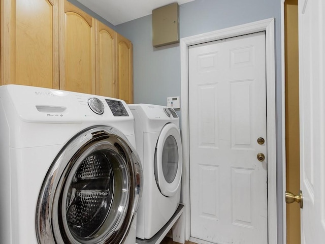 washroom featuring cabinet space and washer and clothes dryer