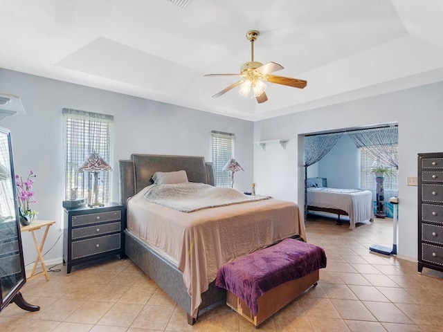 bedroom with a raised ceiling, multiple windows, and light tile patterned floors