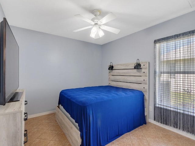 bedroom with ceiling fan, multiple windows, light tile patterned flooring, and baseboards