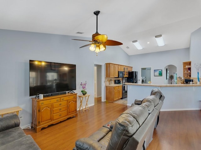 living area featuring arched walkways, lofted ceiling, light wood-style flooring, visible vents, and a ceiling fan