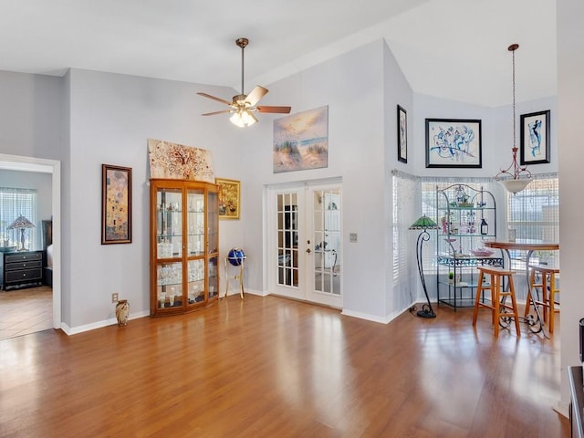 interior space with high vaulted ceiling, french doors, baseboards, and wood finished floors