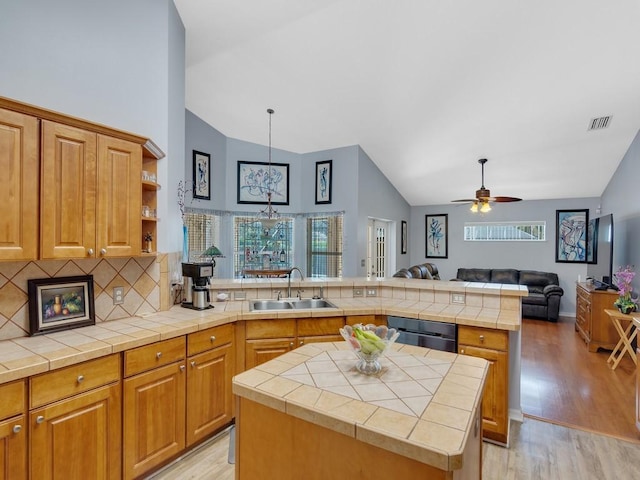 kitchen featuring a peninsula, a kitchen island, a sink, visible vents, and open floor plan