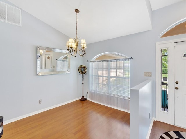 foyer with lofted ceiling, a chandelier, wood finished floors, visible vents, and baseboards