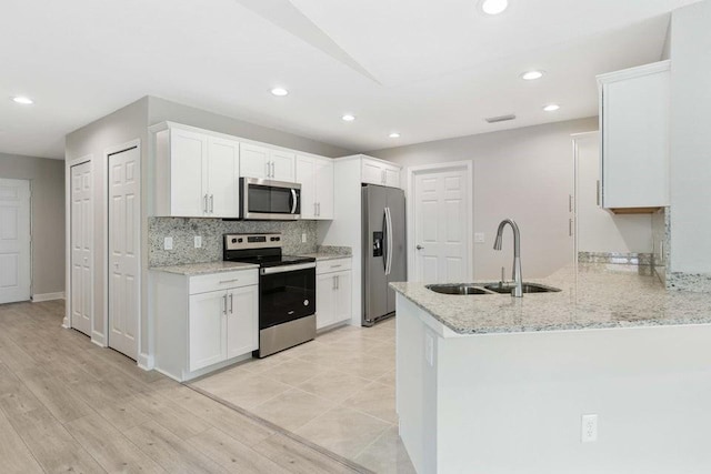 kitchen featuring sink, stainless steel appliances, light hardwood / wood-style flooring, kitchen peninsula, and white cabinets