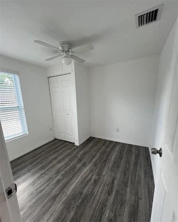 unfurnished bedroom featuring dark hardwood / wood-style flooring, ceiling fan, and a closet