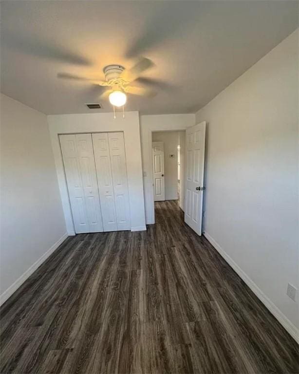 unfurnished bedroom featuring ceiling fan, a closet, and dark wood-type flooring