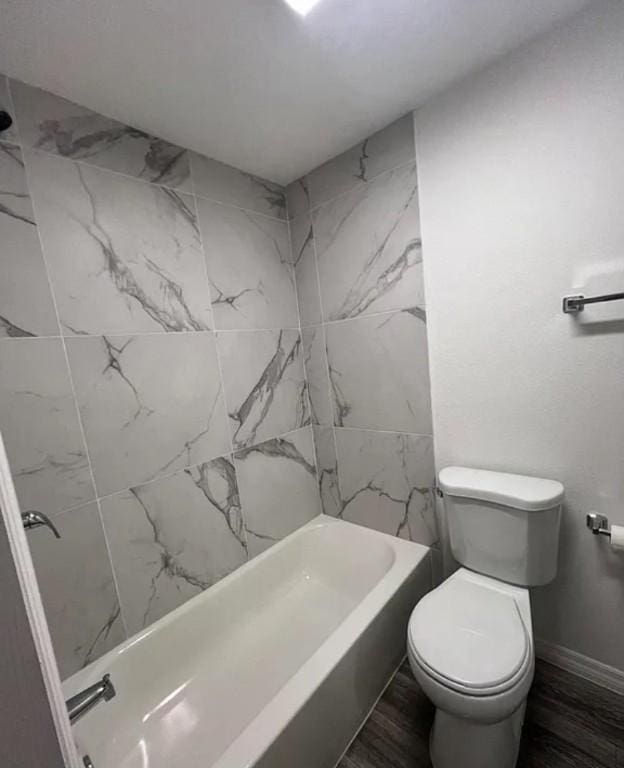 bathroom with toilet and tiled shower / bath