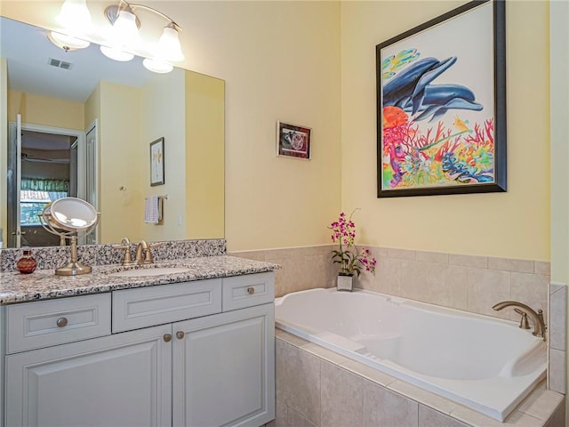 bathroom featuring vanity and a relaxing tiled tub