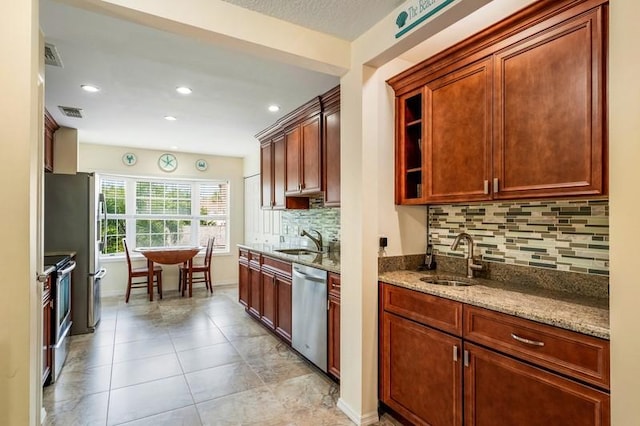 kitchen featuring light tile patterned floors, stainless steel appliances, a sink, and light stone countertops