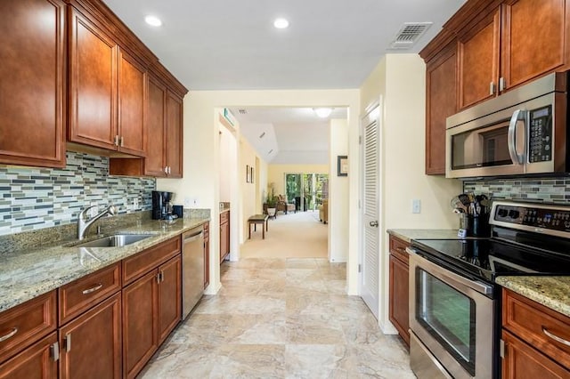 kitchen with visible vents, decorative backsplash, appliances with stainless steel finishes, a sink, and light stone countertops