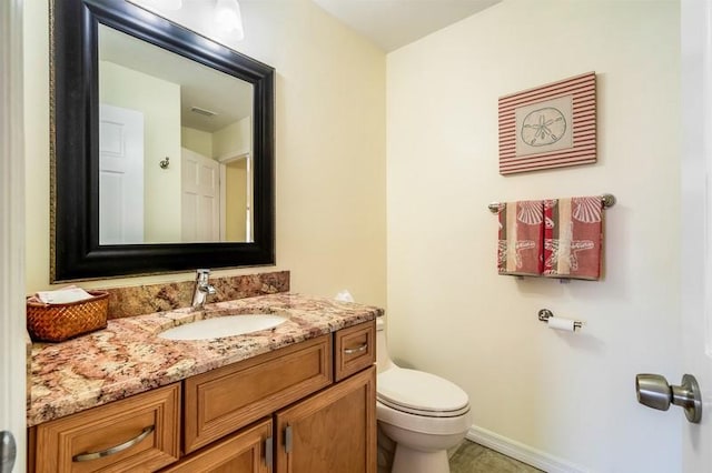 bathroom featuring toilet, baseboards, and vanity