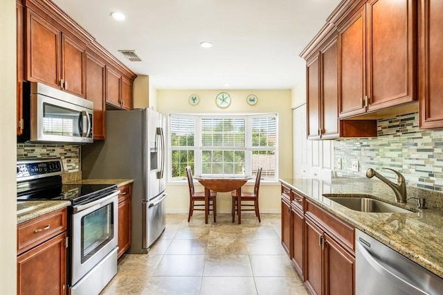 kitchen featuring light stone counters, a sink, visible vents, baseboards, and appliances with stainless steel finishes