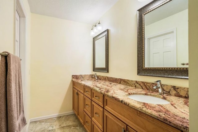 full bathroom with a sink, baseboards, and double vanity